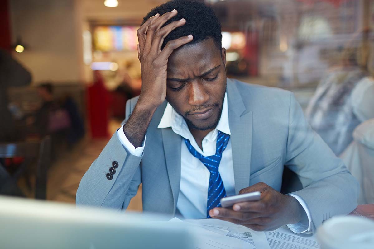 Man Looks at Phone Frustrated with Online Imposters