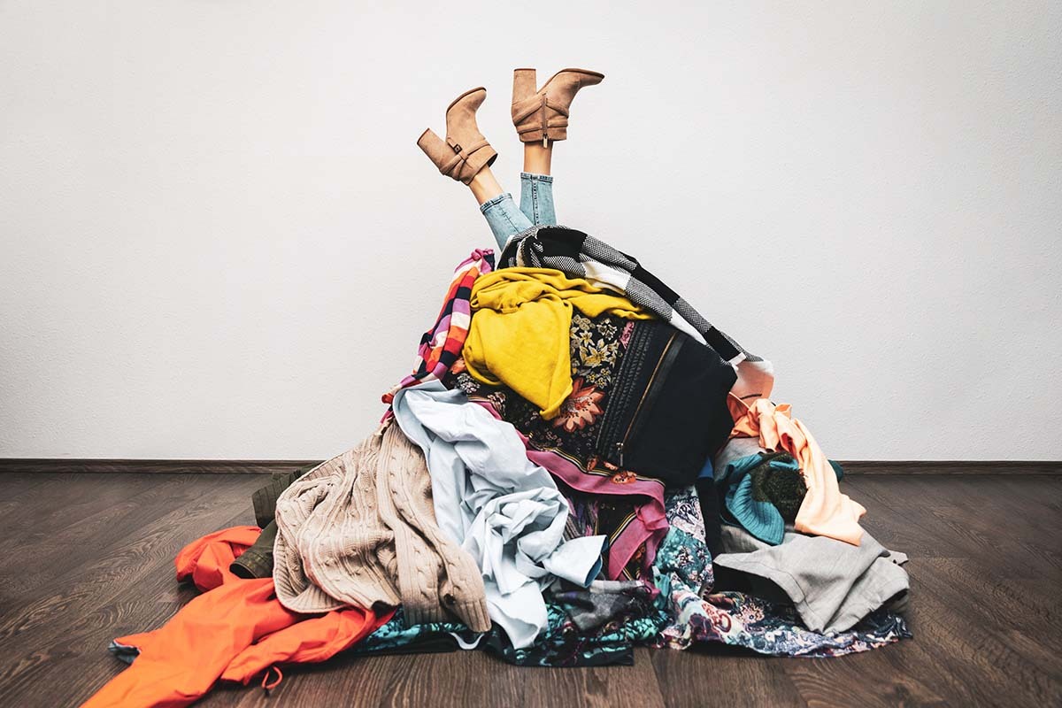 Woman Buried Under Pile of Clothes - Declutter Your Mind