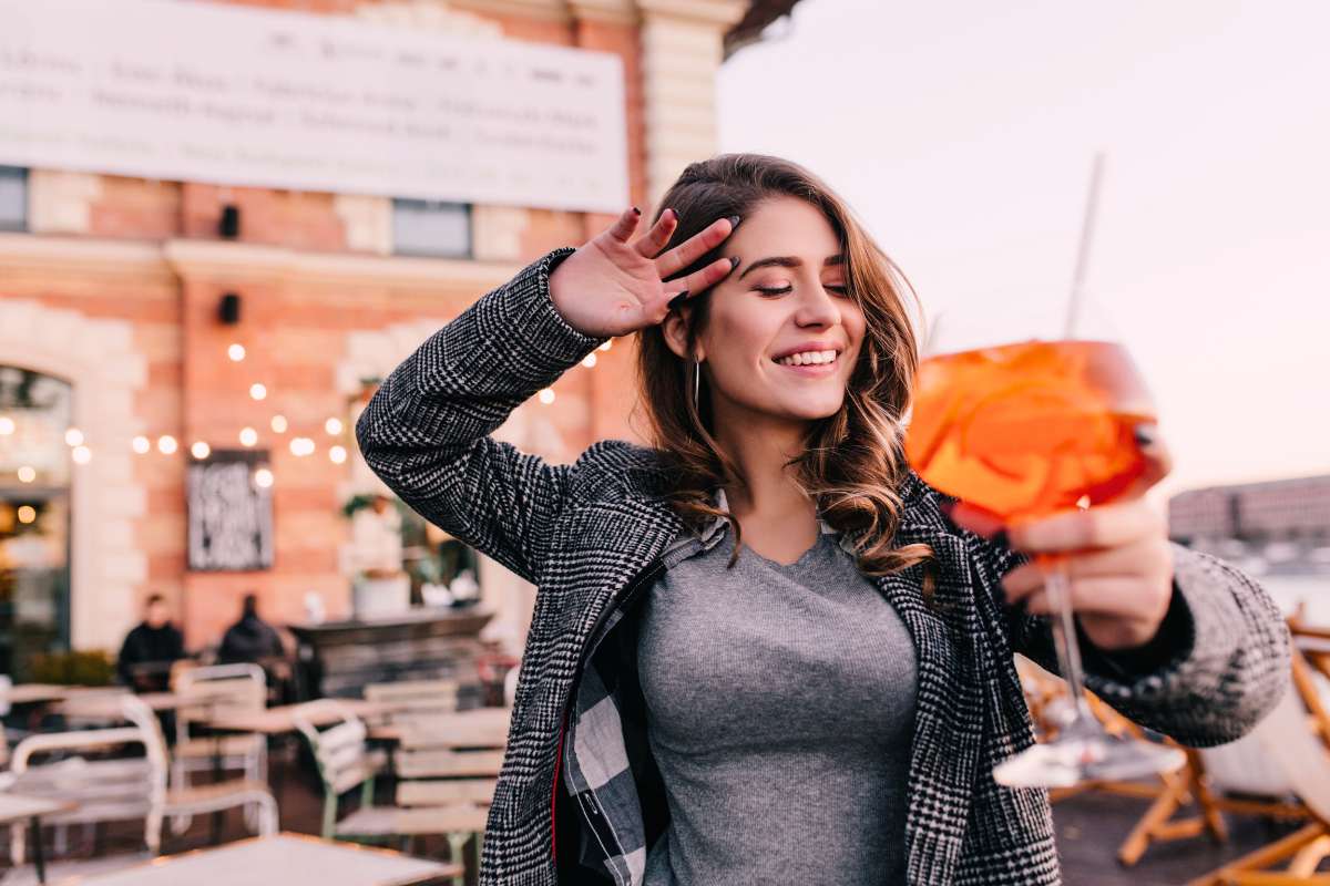 woman dancing while holding cocktail at an outdoor cafe