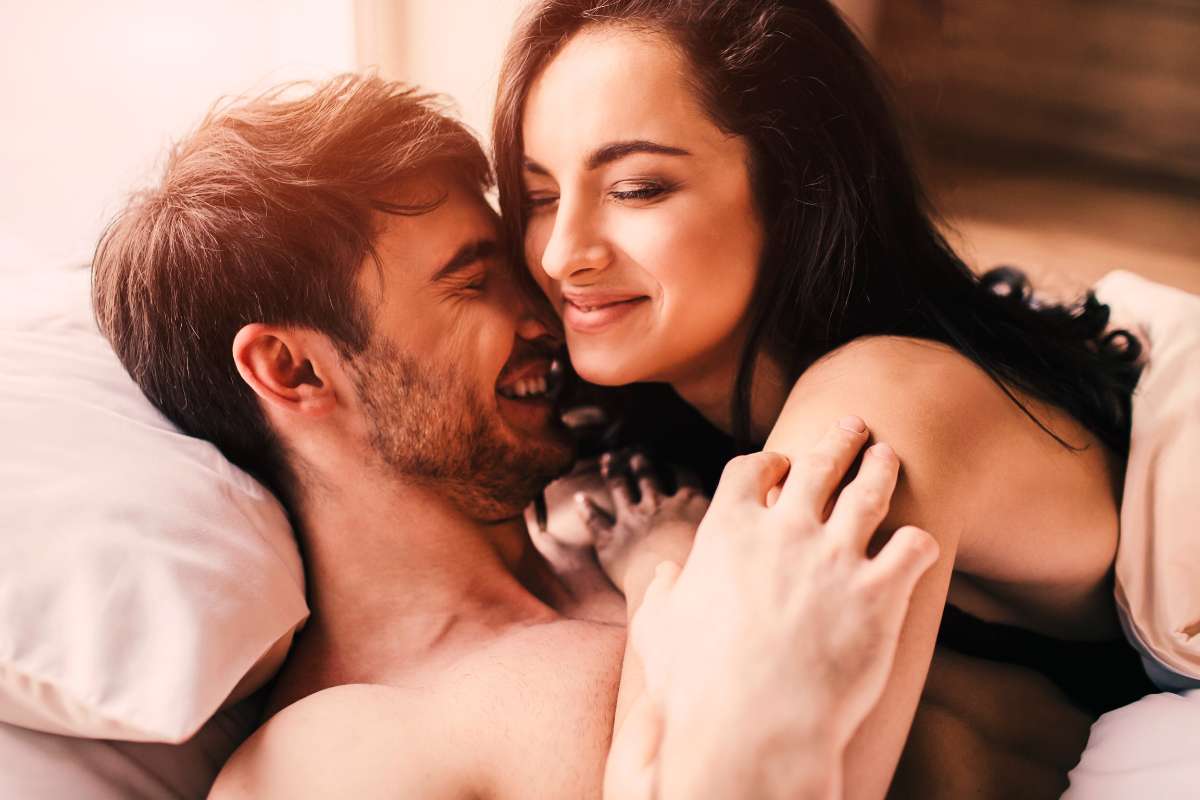 couple cuddling in bed and smiling
