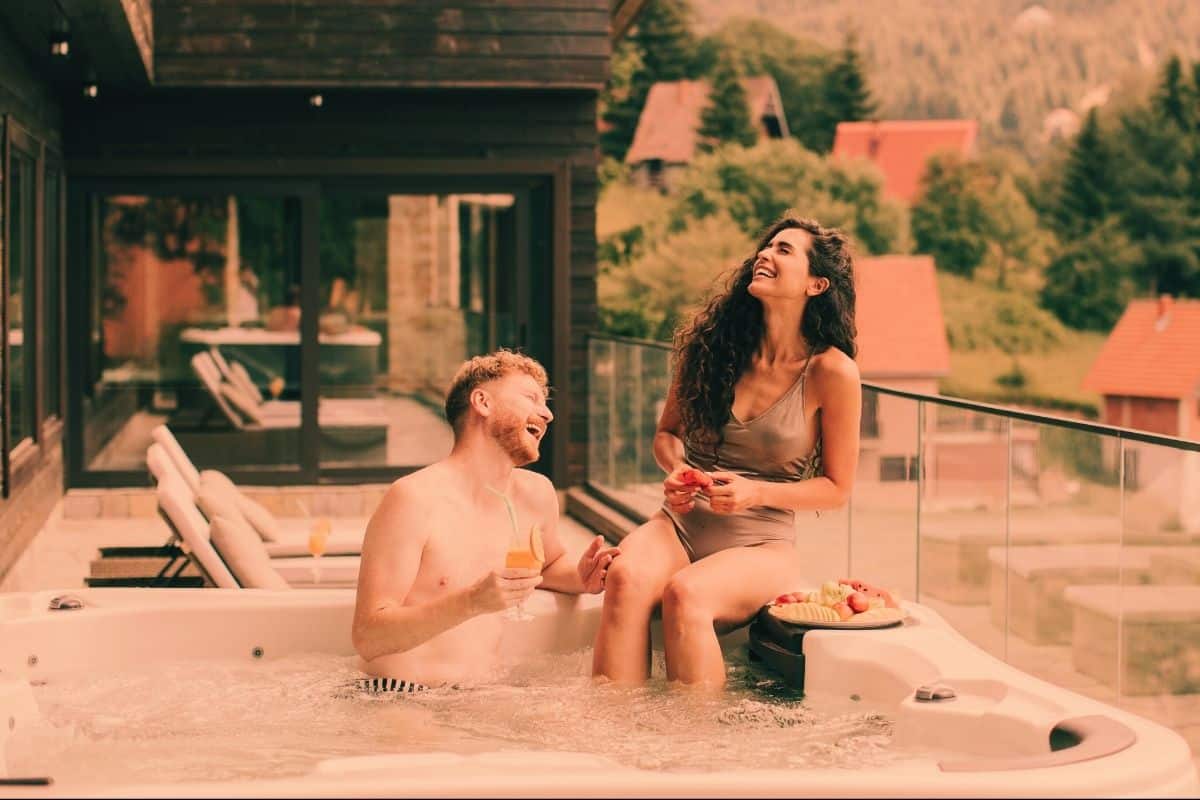 Young couple laughing together in a hot tub on a balcony in the daytime