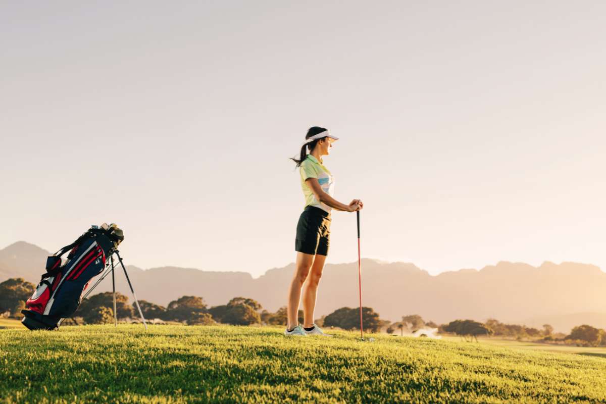 woman on golf course holding her club and looking into the distance