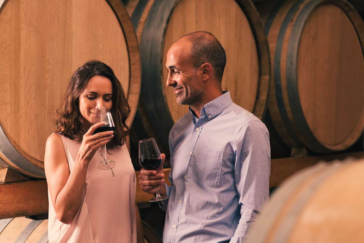 mature couple standing in wine tasting room smiling and drinking wine