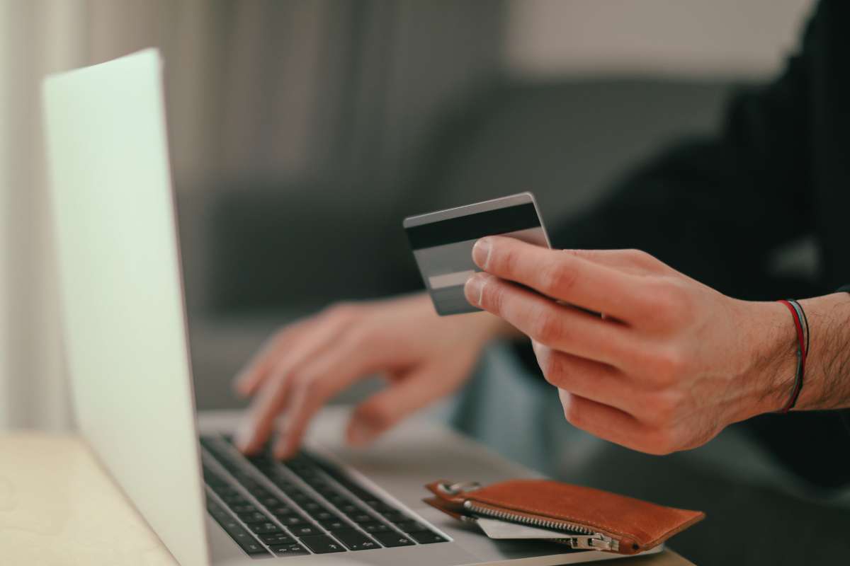 person holding credit card and entering info into computer