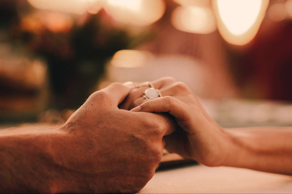 man and woman holding hands at dinner table