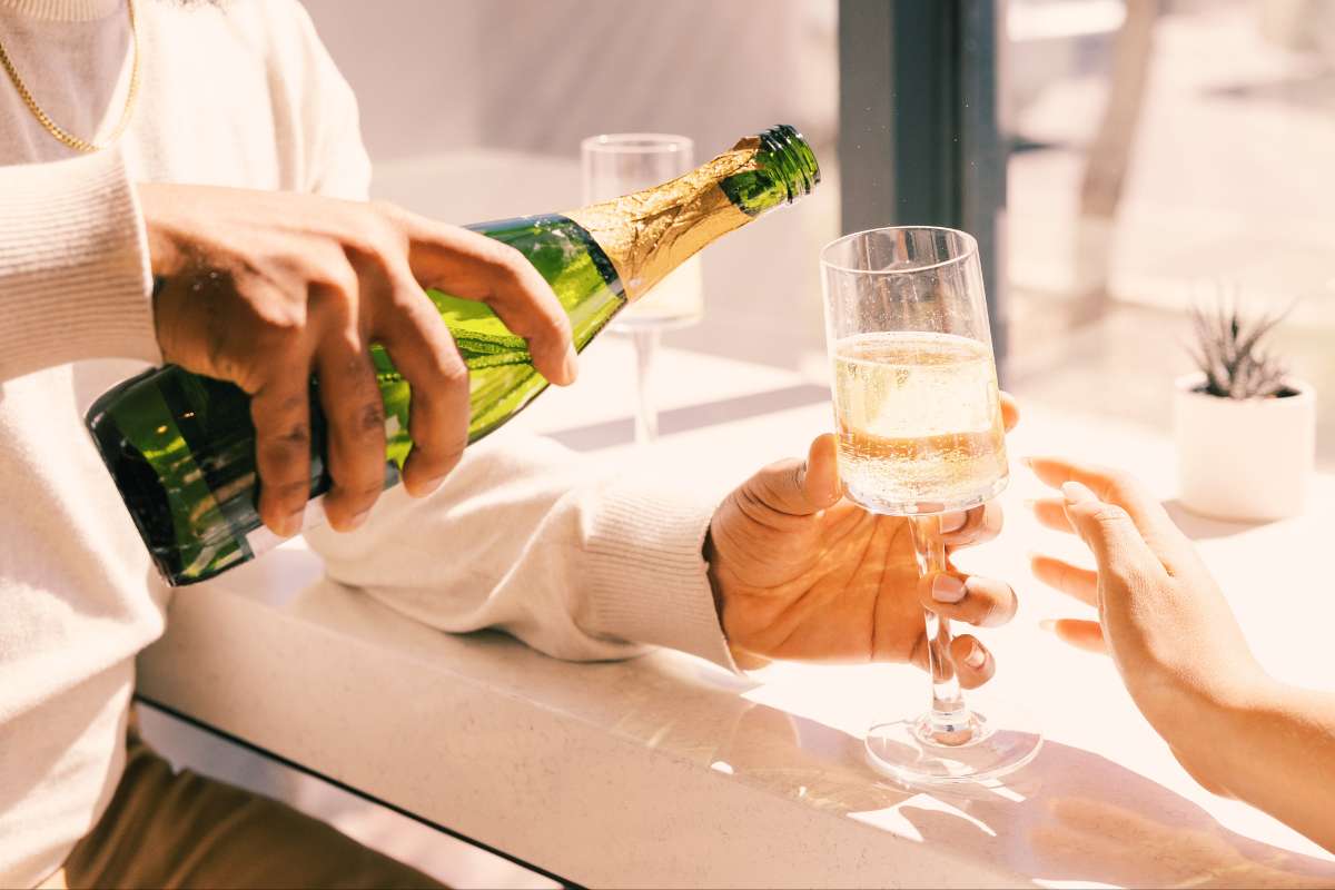 man pouring champagne into a glass for a woman