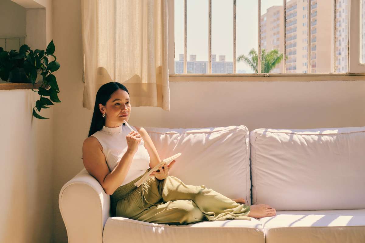 woman sitting on couch writing in a journal