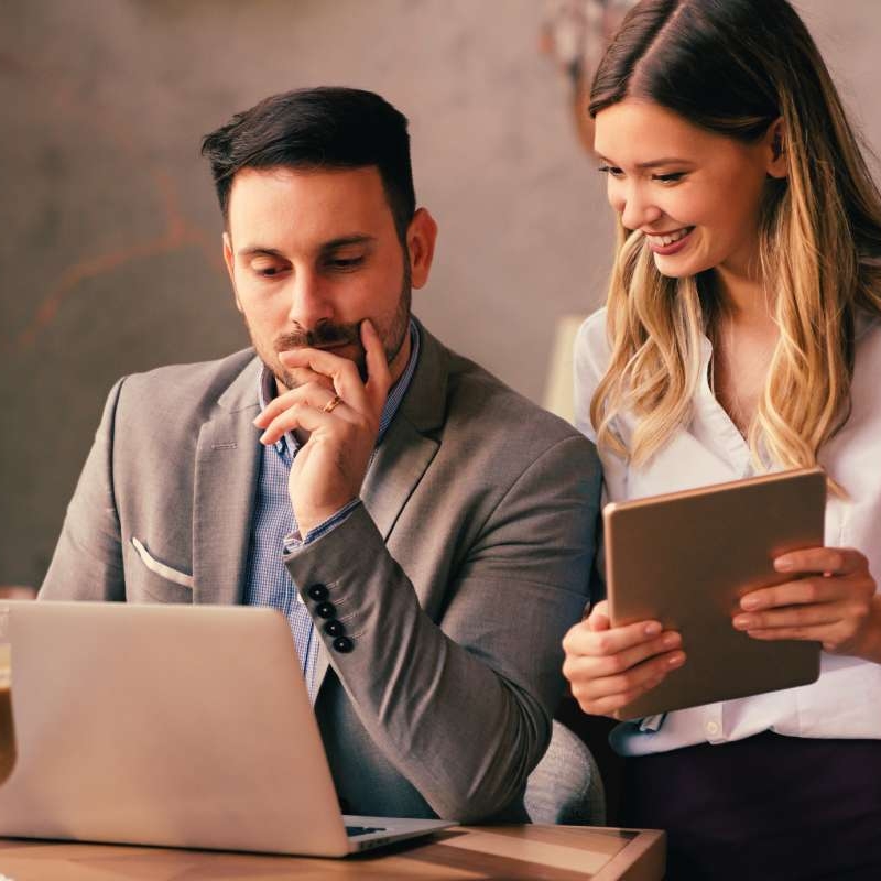 professional man looking at his laptop screen with female friend at table