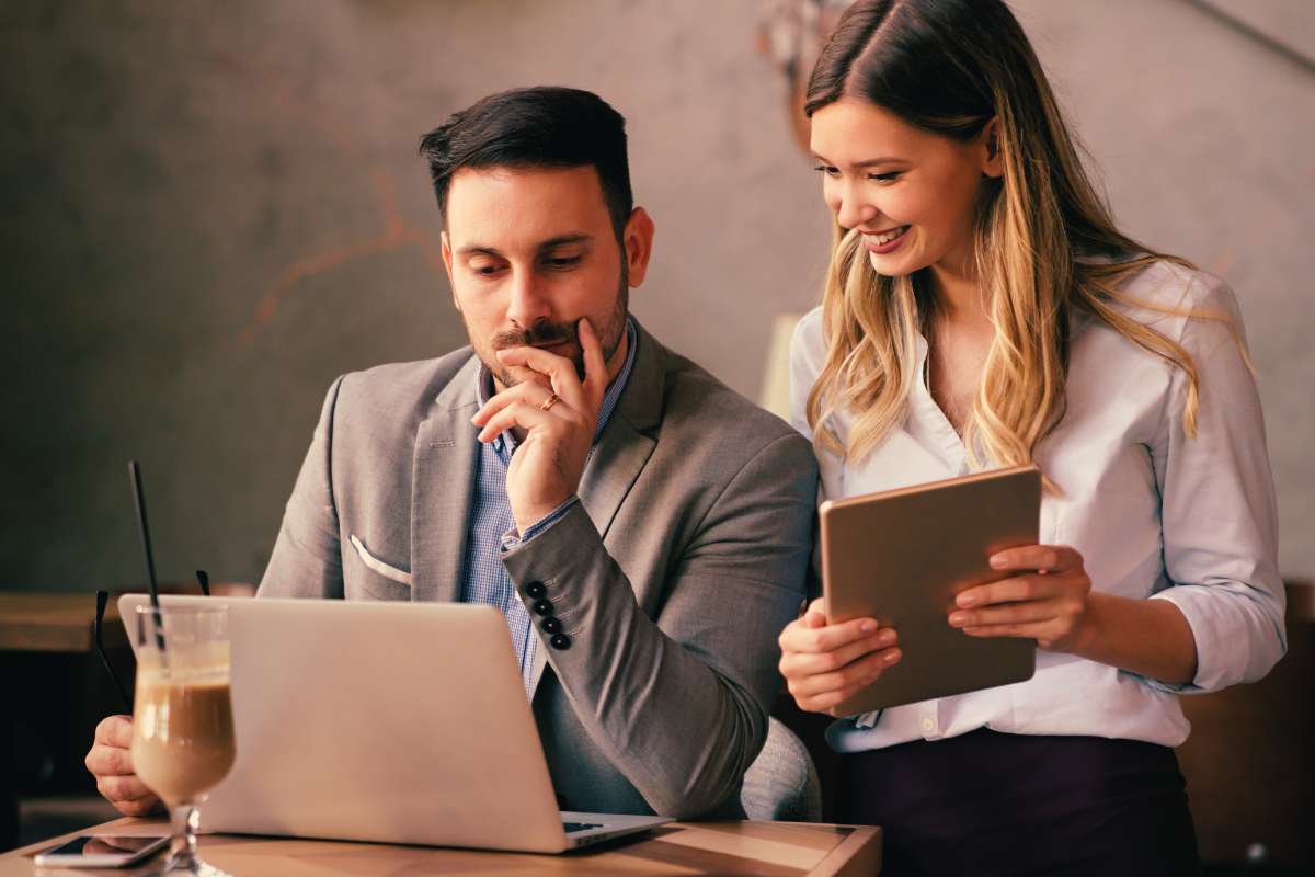 professional man looking at his laptop screen with female friend at table