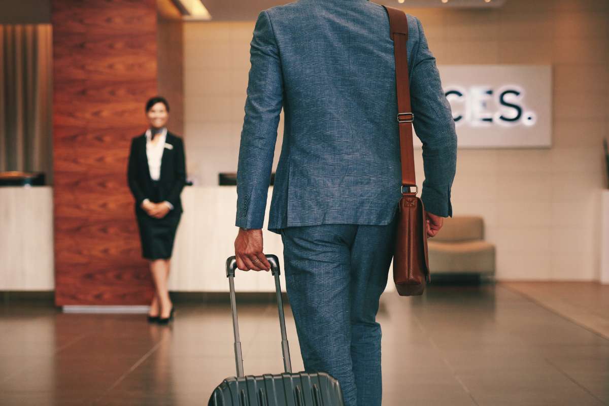 man in suit and roller suitcase walking into hotel lobby