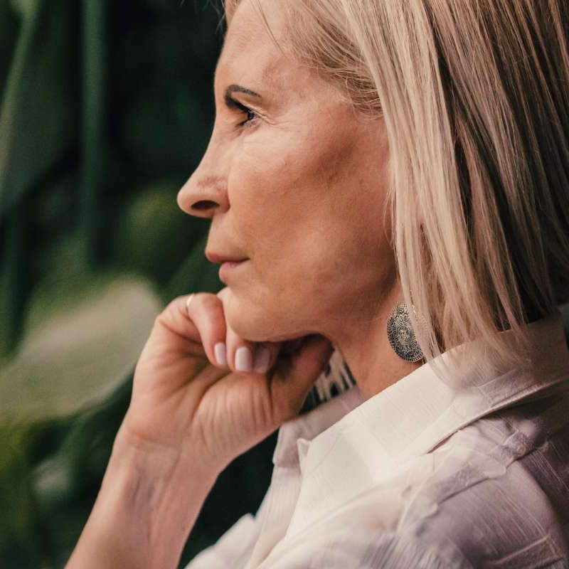 mature older woman looking into the distance with her hand resting on her face