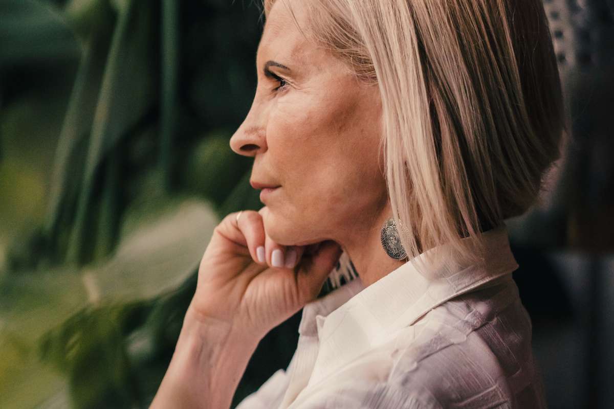 mature older woman looking into the distance with her hand resting on her face