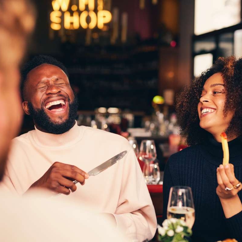 a man and woman laughing in conversation at an upscale lunch table. They know that your lifestyle and love life are deeply connected.