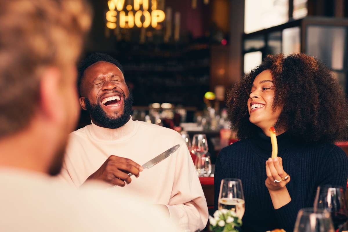a man and woman laughing in conversation at an upscale lunch table. They know that your lifestyle and love life are deeply connected.