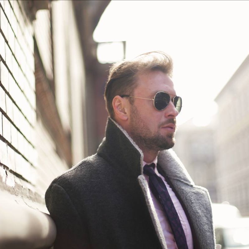 an attractive man in a suit and sunglasses. he is walking confidently, knowing that high-end matchmaking is a good choice for him.