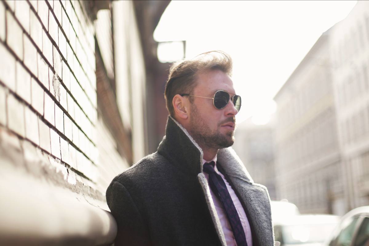an attractive man in a suit and sunglasses. he is walking confidently, knowing that high-end matchmaking is a good choice for him.
