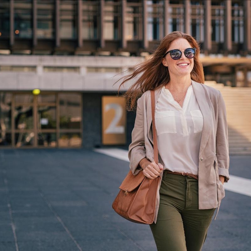 a woman walking outside tall buildings. she is happy to be in a relationship with high emotional intelligence.