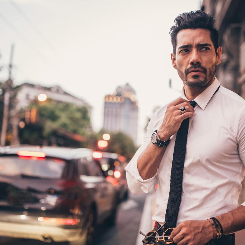 a mna adjusting his tie on a city street. he knows how successful people approach love.