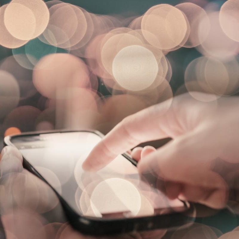 close up of a person's hands using a dating app. Find out what dating apps are really costing you.