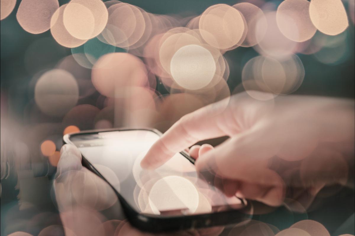 close up of a person's hands using a dating app. Find out what dating apps are really costing you.