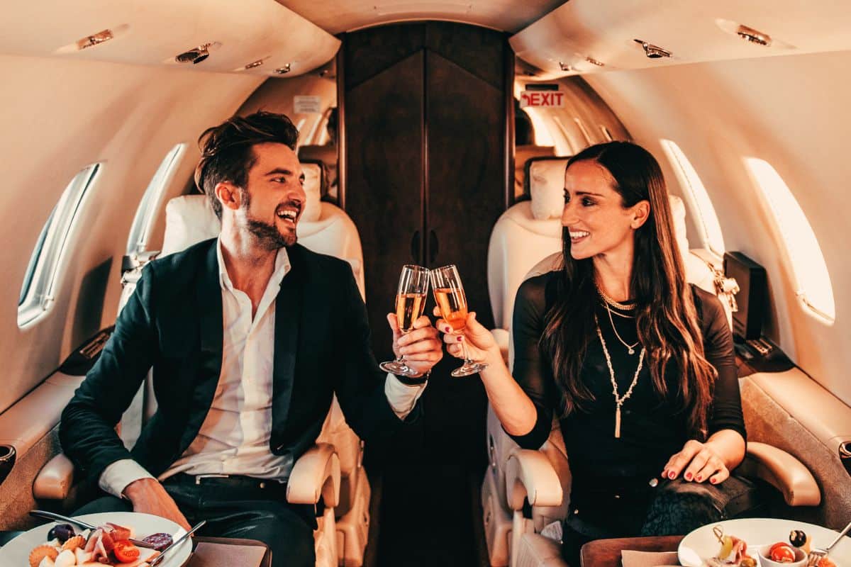 a man and woman on a private jet toasting glasses. They are practicing good date etiquette.